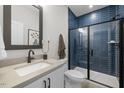 Modern bathroom featuring blue tiled shower with glass door, undermount sink, and sleek fixtures at 4713 Mint Leaf Ln, Raleigh, NC 27612