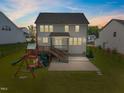 Rear exterior of home featuring a fenced-in yard, deck, patio, and play set, perfect for outdoor enjoyment at 525 Marion Hills Way, Knightdale, NC 27545