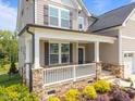 Inviting front porch with stone base, white railings, and a view of the beautifully landscaped yard at 525 Marion Hills Way, Knightdale, NC 27545