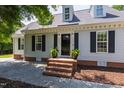 Inviting front entrance with brick steps, potted plants, black shutters, and a black front door at 5413 Lower Creek Ct, Apex, NC 27539