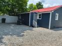 Rear exterior view of the house with gravel, fence, air conditioner and red metal roof at 713 Champion St, Henderson, NC 27536