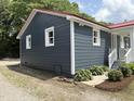 Side view of the gray house with white trim, windows, landscaped yard, and a red metal roof at 713 Champion St, Henderson, NC 27536