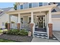 Inviting front porch with brick accents, white railings, and a decorative wreath on the front door at 908 Town Side Dr, Apex, NC 27502
