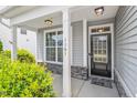 Inviting front porch with a black front door, stone accents, white columns, and manicured landscaping at 1161 Tulip Poplar Rd, Fuquay Varina, NC 27526