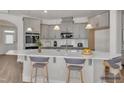 Staged kitchen with gray cabinets, white backsplash, a kitchen island with barstools and stainless steel appliances at 1217 Linkwood Way, Fuquay Varina, NC 27526