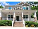 Inviting front porch with brick stairs, stone pillars, white railings, and a cozy space for relaxation at 1304 Double Oak Ln, Willow Springs, NC 27592