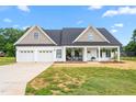 Beautiful home with a covered porch, rocking chairs, swing, two-car garage, and lush green lawn at 1711 Memory Ln, Burlington, NC 27217