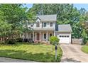 Charming two-story home with a covered front porch, lush landscaping, and an attached two-car garage at 19 Knightsbridge Ct, Durham, NC 27707