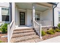 Inviting front porch with brick steps, white railings, and a modern front door adorned with a wreath at 1928 Vandiver Way, Apex, NC 27523