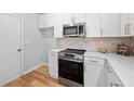 The kitchen features stainless steel appliances, white cabinets, stone countertops and a light tile backsplash at 2040 Persimmon Ridge Dr, Raleigh, NC 27604