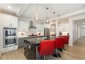 Bright kitchen features stainless steel appliances, modern cabinetry, and a large island with marble accents and pendant lighting at 311 Horseshoe Pl, Angier, NC 27501