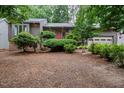 Charming exterior view of a home featuring a landscaped yard with mature trees and a pink front door at 3285 Edinburgh Dr, Sanford, NC 27332