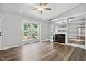 Bright living room with modern ceiling fan, a fireplace flanked by built-in bookshelves, and wood flooring at 5911 Westcreek Pl, Raleigh, NC 27606