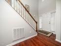 A bright foyer with hardwood floors, white door, and stairs with wooden railing at 1209 Partington St, Wake Forest, NC 27587