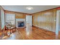 Inviting living room with wood-paneled walls, a brick fireplace, and gleaming hardwood floors at 171 Magnolia Dr, Roxboro, NC 27573