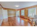 Bright living room featuring wood-paneled walls, hardwood floors, and natural light from the windows at 171 Magnolia Dr, Roxboro, NC 27573