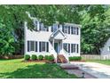 Two-story home featuring black shutters, a well-manicured lawn, and a brick pathway leading to the front entrance at 1905 Indianwood Ct, Raleigh, NC 27604
