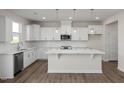Bright kitchen with white cabinets, stainless steel appliances, a large island, and modern pendant lighting at 267 Old Fashioned Way, Lillington, NC 27546