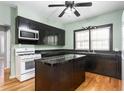 Galley kitchen with black cabinetry, light-green walls, an island, and a white gas range at 307 W Austin St, Mebane, NC 27302
