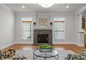 Cozy living room featuring a stone fireplace, crown molding, and natural light from the many windows at 4913 Great Meadows Ct, Raleigh, NC 27609