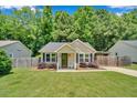 Inviting single-story home with a quaint porch, surrounded by vibrant green lawn and mature trees at 512 Wyndham Dr, Fuquay Varina, NC 27526