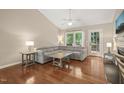Spacious living room featuring hardwood floors, vaulted ceiling, and a comfortable gray sectional sofa near large windows at 5441 Millrace Trl, Raleigh, NC 27606