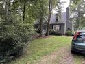 View of the home's exterior showcasing mature trees, green grass, and driveway at 5816 Henner Pl, Durham, NC 27713