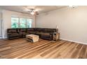Open-concept living room features wood flooring, a ceiling fan, and large windows that fill the room with light at 6206 Braidwood Court Ct, Raleigh, NC 27612