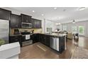 Modern kitchen features stainless steel appliances, dark cabinetry, granite countertops, and hardwood floors at 6236 Pesta Ct, Raleigh, NC 27612