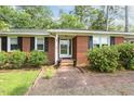 Close up of a charming brick home's entryway, complete with a brick walkway and black shutters at 780 Leslie Campbell Ave, Lillington, NC 27546