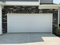 The two-car garage features a white door and stone accents at 1116 Sidney Creek Dr # 1116, Zebulon, NC 27597