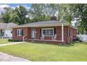 Classic brick home featuring a well-kept lawn, quaint front porch with rocking chairs, and appealing architectural details at 208 S College Ave, Kenly, NC 27542