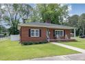 Well-maintained brick home with a lush front lawn, welcoming porch with rocking chairs, and charming curb appeal at 208 S College Ave, Kenly, NC 27542