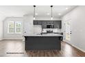 Modern kitchen features gray cabinets, stainless steel appliances, and island with granite countertop at 325 Bluejay St, Clayton, NC 27520