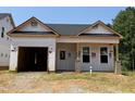 New home under construction features an open garage and covered porch with brick supports against a backdrop of trees at 335 Bluejay St, Clayton, NC 27520
