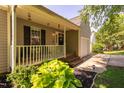 Inviting covered porch with white railings, black door with wreath, and landscaped garden at 358 Tillamook Dr, Wake Forest, NC 27587