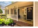 Inviting front porch with black shutters, black door with wreath, potted plants and garden at 358 Tillamook Dr, Wake Forest, NC 27587