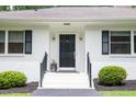 Inviting front door entrance with sleek black door, white stairs, and manicured shrubs at 3934 Hope Valley Rd, Durham, NC 27707