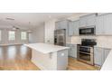 An open-concept kitchen with stainless steel appliances, gray cabinets, and a large island open to living area at 503 Gateway Townes Blvd, Wake Forest, NC 27587