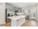 A modern kitchen with stainless steel appliances, light gray cabinets, and a center island with a white countertop at 503 Gateway Townes Blvd, Wake Forest, NC 27587