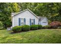 Side exterior of a home with landscaped yard, tidy shrubbery, and attached garage at 5405 Swordsman Ct, Knightdale, NC 27545