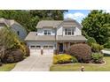 Beautiful two-story home with a two-car garage, manicured landscaping, and inviting front porch with stone and wood details at 5545 Moneta Ln, Apex, NC 27539