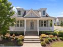 Charming home featuring dormer windows, a welcoming front porch with white columns and manicured landscaping at 1000 Groveview Wynd, Wendell, NC 27591