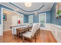 Elegant dining room with blue walls, wainscoting, hardwood floors and a large table set for dinner at 1230 Golden Bluff Ln, Fuquay Varina, NC 27526