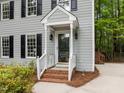 Close-up of front porch with brick steps, white railings, and black door at 15 Gray Fox Ct, Durham, NC 27713