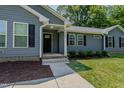 Inviting front entrance featuring a covered porch, black door, and nicely landscaped garden beds at 169 Forest Dr, Graham, NC 27253