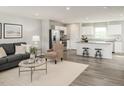 Open-concept living area with modern gray couch and stainless steel kitchen appliances at 224 Rosewood Dr, Sanford, NC 27330