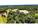 Aerial view showcases a home and several agricultural buildings surrounded by fields and lush, green forest at 2642 Holly Springs Church Rd, Broadway, NC 27505