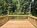 Picture of the back deck of the home with wood planks and railings overlooking trees in the background at 311 Rothbury Ct, Sanford, NC 27330