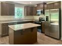 Well-lit kitchen featuring stainless steel appliances, granite countertops, and wood cabinets at 311 Rothbury Ct, Sanford, NC 27330